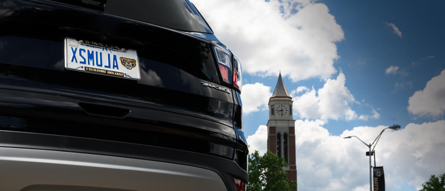 A black Ford Escape with an OU license plate that reads A L U M 2 X